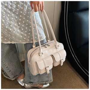 Detailed close-up of cream textured leather shoulder bag with buckle pockets and silver zip