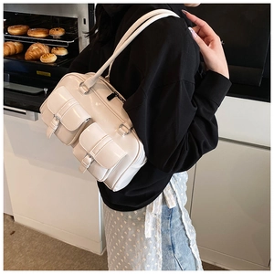 Close-up of a stylish cream shoulder bag with decorative buckle pockets in a warm kitchen