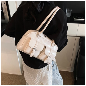 Model wearing a cream Boston shoulder bag with silver buckles and dual front pockets