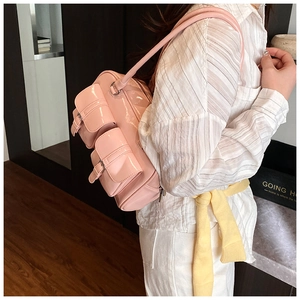 Detailed side view of pink patent leather shoulder bag with multi-pocket utility design