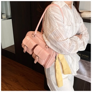Detail view of pink glossy shoulder bag with multiple buckle pockets and silver hardware
