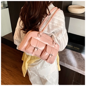 Close-up of pink patent leather shoulder bag with buckle pockets in a lifestyle setting