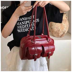 Close-up of vintage burgundy glossy leather bag with dual front buckle pockets