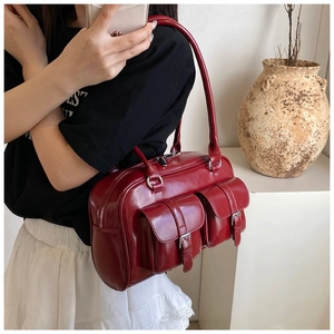 Detail of red patent leather shoulder bag with vintage buckles and glossy finish