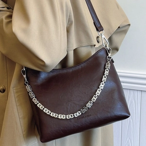 Deep brown matte leather bucket bag with metallic chain and shoulder strap on model