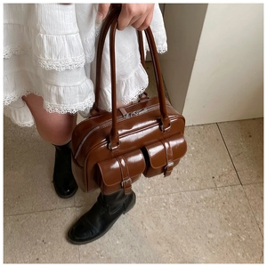 Close-up of vintage brown glossy PU leather handbag with front utility cargo pockets