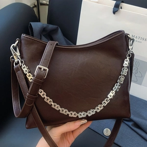 Deep brown oil-wax leather bucket bag with silver geometric chain strap and adjustable belt