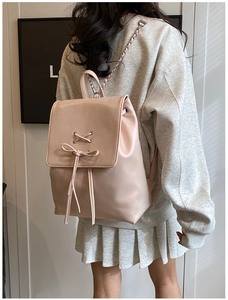 Detailansicht eines rosa Rucksacks mit Lederstruktur und dekorativer Bandschleife