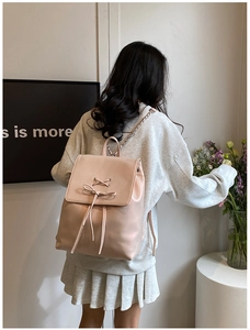 Detail eines rosa Kunstleder Rucksacks mit dekorativer Schnürung und Kettenträgern