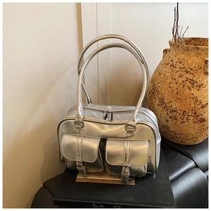 Detail of silver metallic handbag with dual front buckle pockets and long shoulder straps