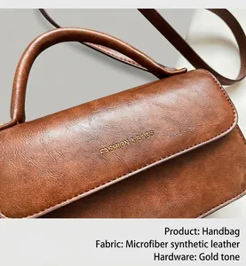 Gros plan sur la texture du cuir vintage marron et logo doré sur le sac à main