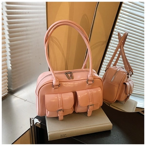 Close-up of pink patent leather shoulder bag with buckle pockets and top zipper detail