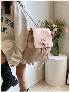 Detail eines hellrosa Kunstleder-Rucksacks mit Schnürschleife und goldenen Ketten