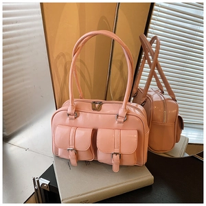 Detail of pink patent leather shoulder bag with double buckled pockets and silver hardware