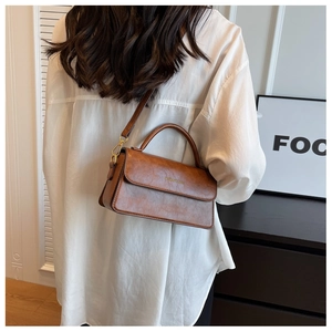 Gros plan d'un sac à main vintage marron en cuir avec bandoulière réglable sur un mannequin