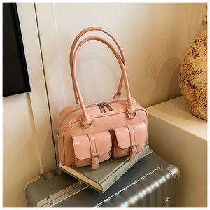 Detail of a pink glossy handbag featuring twin front buckled pockets on a silver suitcase