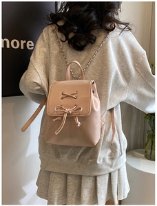 Rückansicht eines hellrosa Mini-Rucksacks mit Schleife und Silberkette an einem Modell
