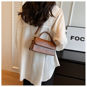 Détail d'un sac bandoulière vintage marron avec poignée et bandoulière amovible