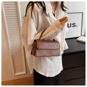 Gros plan du sac à main marron vintage avec boucle dorée et texte en relief élégant