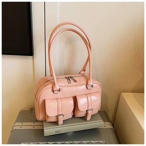 Detailed view of pink glossy PU leather handbag with front pockets and silver buckles