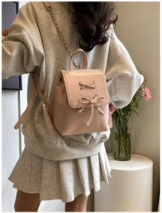 Detailansicht des rosa Leder-Minirucksacks mit dekorativer Schleife und Kettenriemen