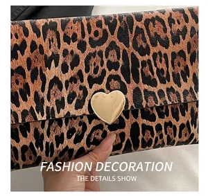 Détail d'une pochette léopard avec fermoir coeur doré et texture en cuir élégante