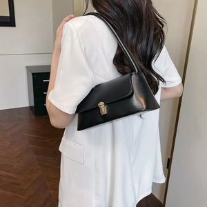 Sac sous le bras en cuir noir mat minimaliste avec fermoir doré sur blazer blanc
