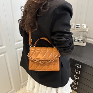 Brown quilted crossbody bag with triangular stitching and decorative plastic chain