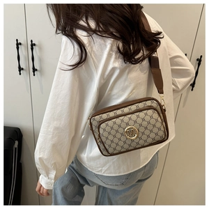 Detail view of vintage patterned crossbody bag with gold M logo and wide shoulder strap