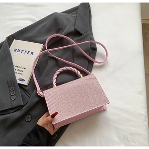Macro view of pink glitter handbag with twisted top handle and gold hardware detail