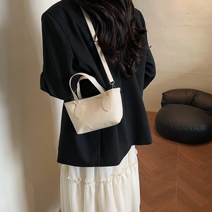 Chic beige lychee grain bucket bag with handles and crossbody strap on a model