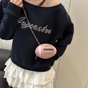 Rosafarbene Umhängetasche in Rugbyform mit goldener Kette am Modell im Freizeitlook
