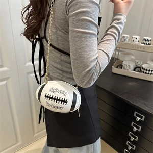 Minimalistische Leder-Umhängetasche in Rugby-Form mit goldener Kette an einem Model