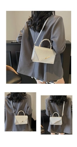 Detail of silver crossbody bag featuring rhinestone flap and woven metal handle