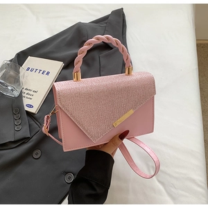 Detail of pink rhinestone handbag with woven handle and gold hardware in a lifestyle setting