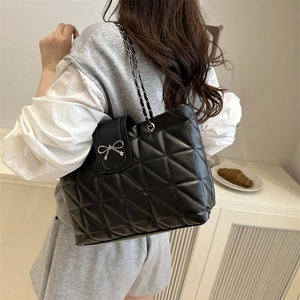 Large black quilted tote bag with silver bow accent and chain shoulder strap for women
