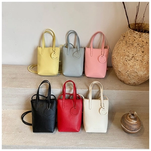 Minimalist tote bags in six colors arranged on stone steps with smiley face charms