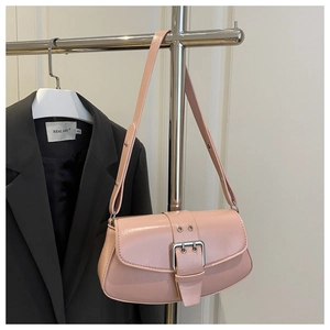 Close-up of pink glossy saddle bag with silver metal buckles and eyelet details