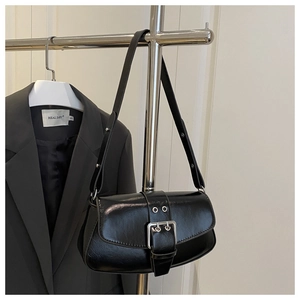 Detail of a minimalist black polished saddle bag with silver buckle on a metal hanger