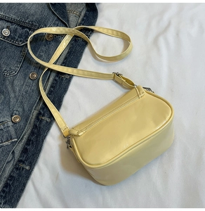 Detail of light yellow glossy crossbody bag with silver hardware and adjustable strap