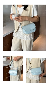 Detailed view of light blue glossy patent leather crossbody bag with adjustable strap
