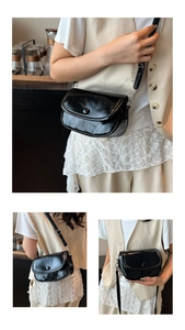 Detail of black glossy saddle bag with round magnetic button and silver hardware