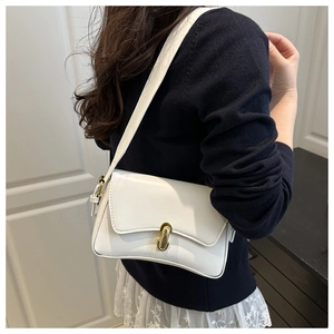 Detail of white faux leather baguette bag with elegant golden U-shaped metal clasp