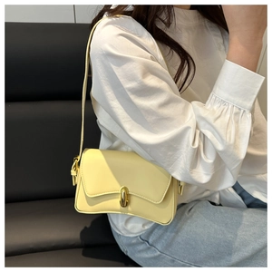 Detail of minimalist pale yellow underarm bag with elegant gold buckle and leather texture