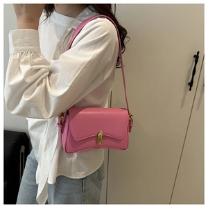 Barbie pink matte leather underarm bag with gold twist lock and curved bottom on model
