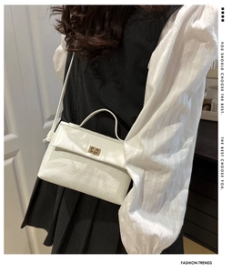 Close-up of white embossed leather crossbody bag with elegant golden turn-lock closure