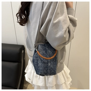 Gros plan d'un sac bandoulière rétro en denim à pois blancs avec chaîne métallique