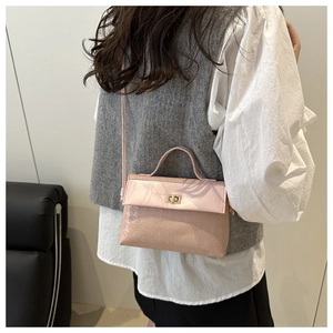 Detailed view of pink embossed handbag with gold clasp worn as a crossbody bag