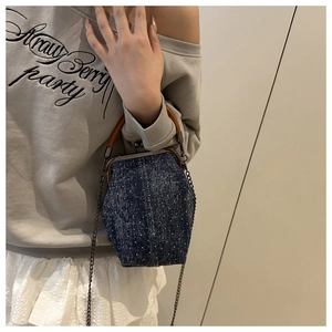 Détail du sac seau en denim avec poignée en bois et chaîne en métal sur un modèle