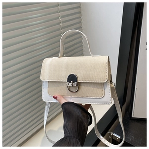 Detail of silver twist lock and beige woven texture on the mini crossbody handbag